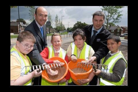 Schoolchildren involved in sowing grass during landscaping